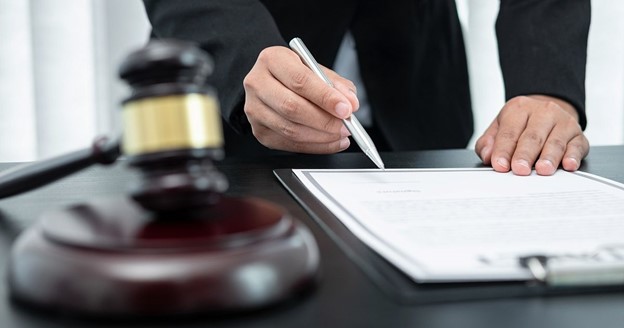 lawyer with pen in hand and gavel on table 