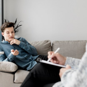 man laying on couch talking with someone in a chair with pen and notepad