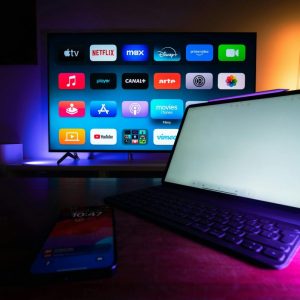 tv screen turned on showing apps on the screen, with tablet and phone on table