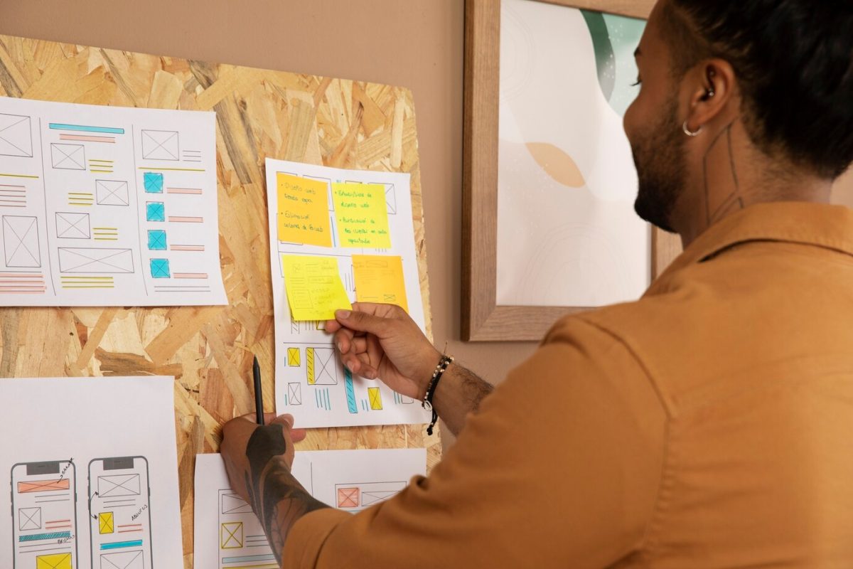 man putting sticky notes on a paper on a bulletin board