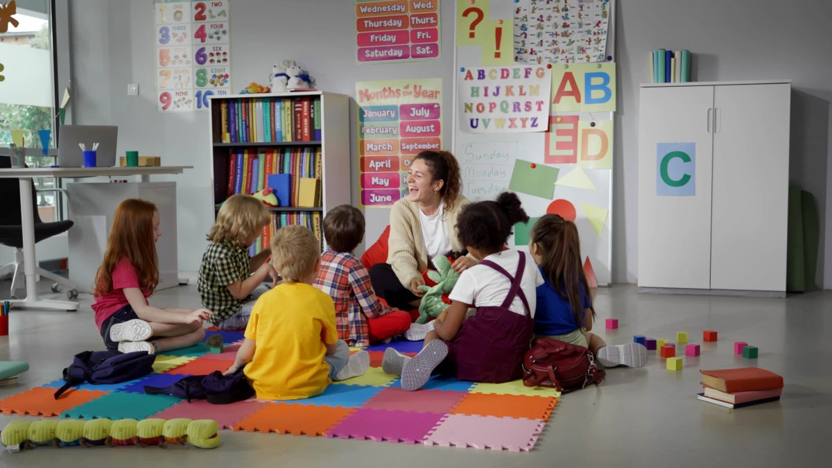 teacher sitting with students on carpet