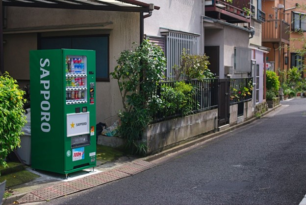 green sapparo vending machine sitting on edge of street