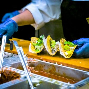 person making tacos at a taco bar