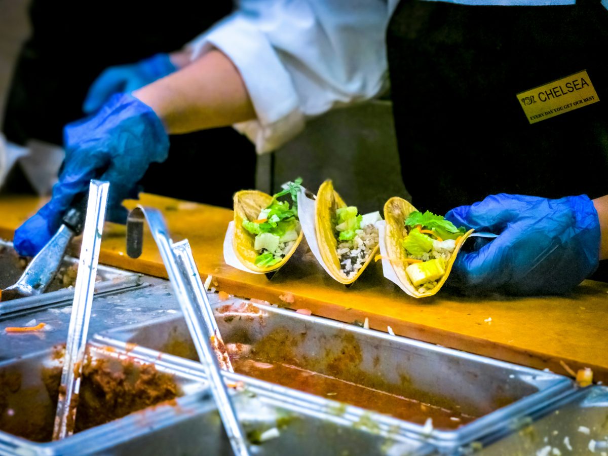 person making tacos at a taco bar