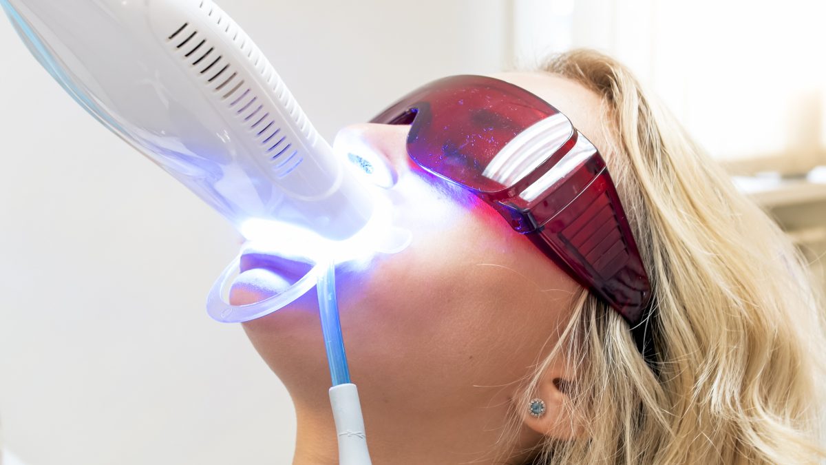 girl with glasses getting teeth whittened at dentist
