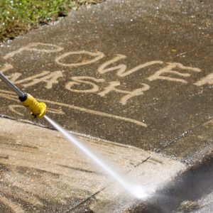 power wash written on dirty side walk with pressure washer