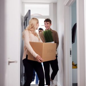 woman with moving box walking into an apartment