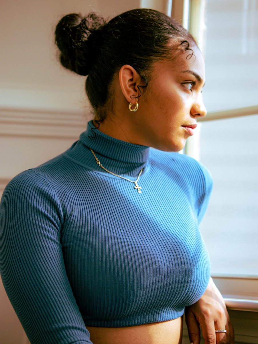 woman looking out the window wearing a blue turtleneck crop top
