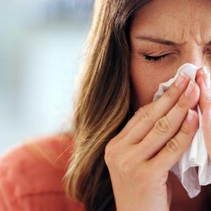 woman sneezing into a napkin