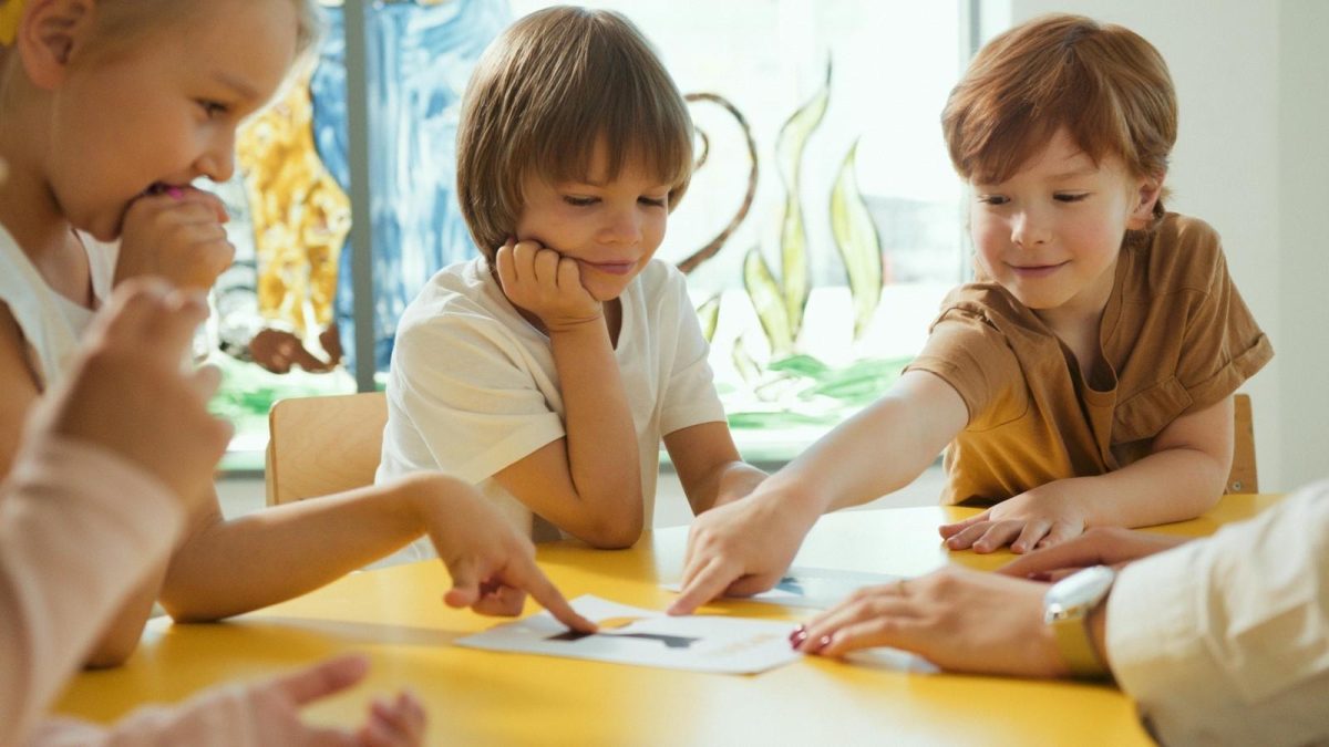 children pointing their fingers to a placecard on a table