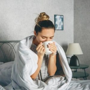 girl sitting in the bed sipping coffee out of a cup