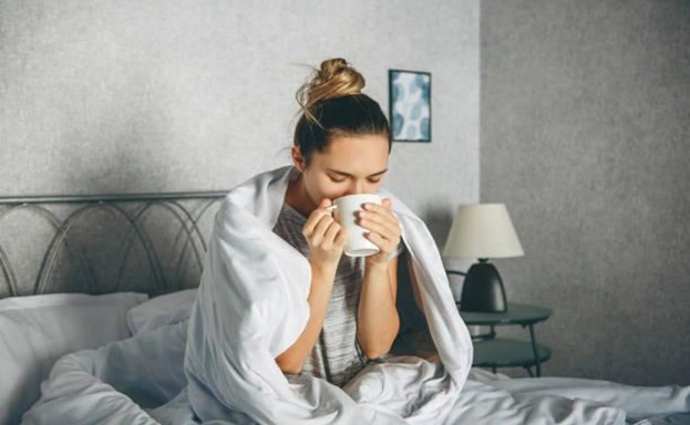 girl sitting in the bed sipping coffee out of a cup