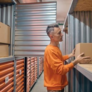 man putting a box on a shelf in a storage building