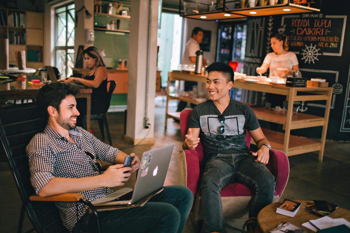 two men at a coffee house sitting in chairs having a conversation