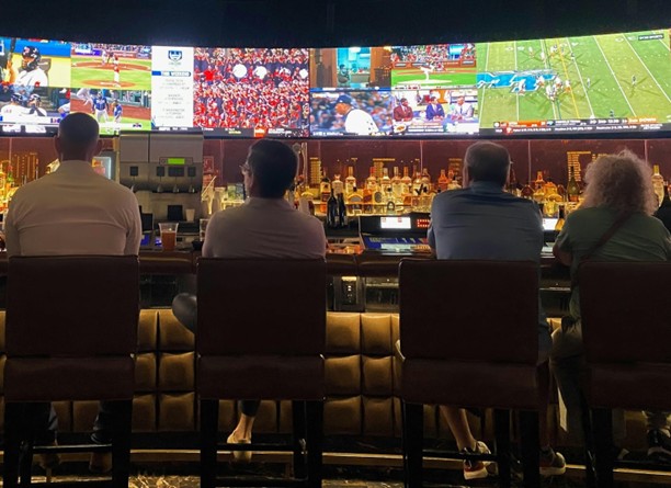 group of men sitting at a bar watching tv
