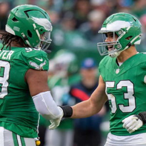 two football players shake hands wearing green unifrom