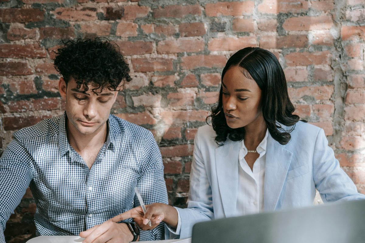 ceo sits with assistant and goes over paperwork