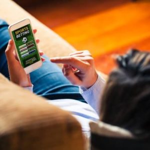 person on a couch holding a phone sports betting