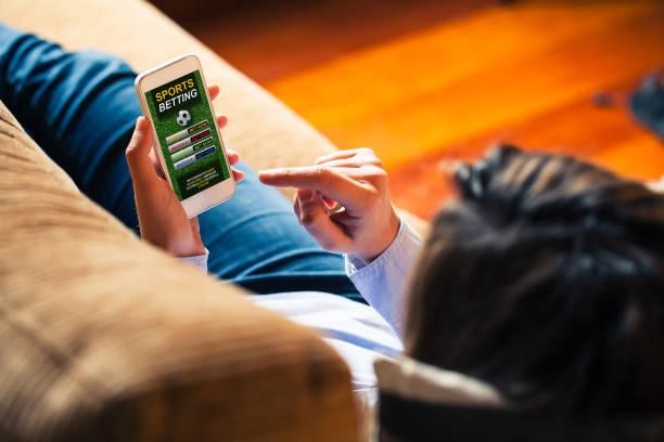 person on a couch holding a phone sports betting