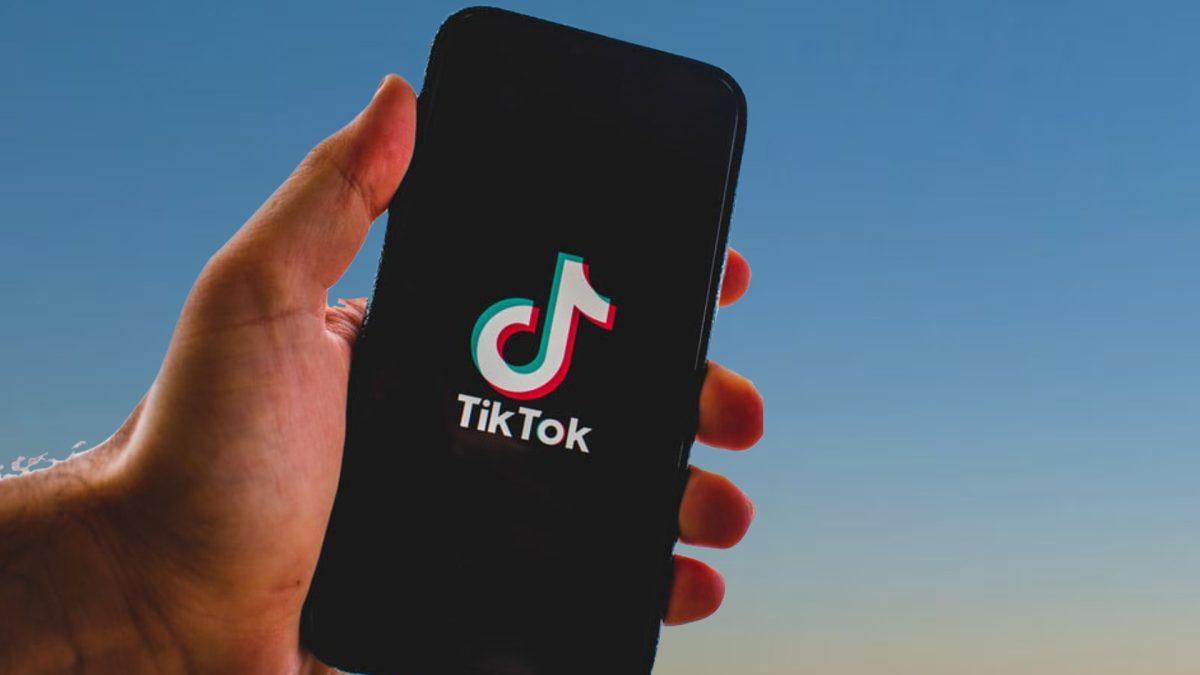 Person holding a phone with TikTok logo on the screen