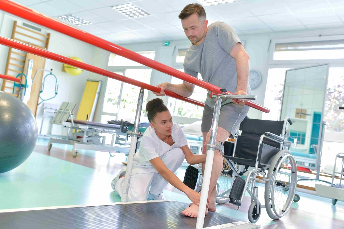 (Occupational therapist helping patient to walk)