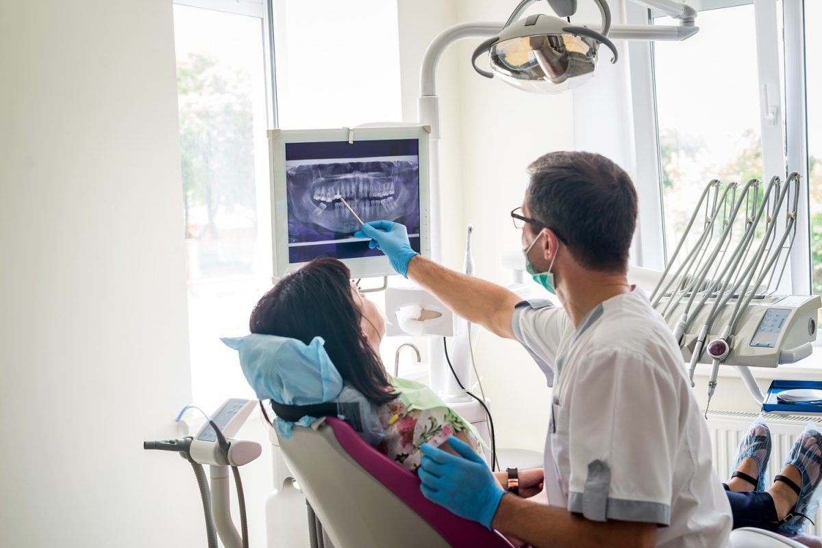 dentist points to xray on screen with patient in chair