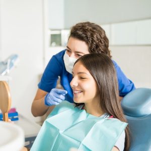 female dentist shows patient teeth in mirror