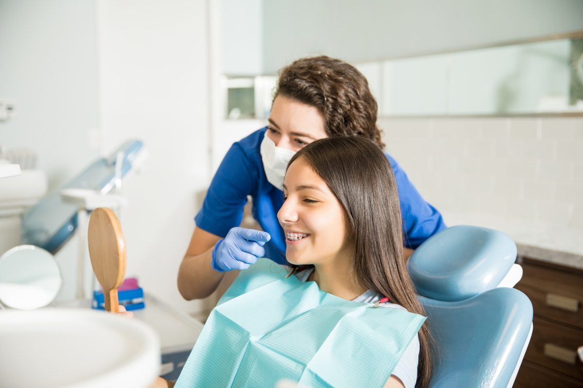 female dentist shows patient teeth in mirror
