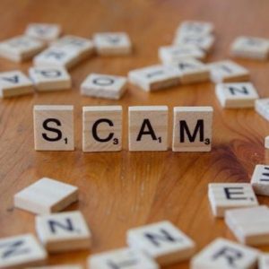 Scam spelled with Scrabble letters on a wooden surface
