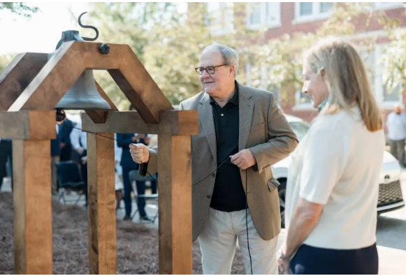 John Cox, great-grandson of Mark Perrin Lowrey Berry, the last president of Hillman College, rings the Hillman Bell to summon attendees to Mississippi College's 200th academic session while his sister, Carol Heidelberg, observes.