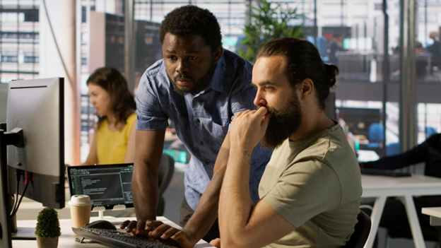 two men looking at a computer screen in an office