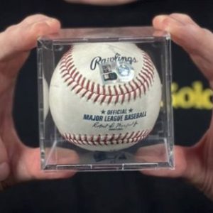 A person holding a baseball in a clear box