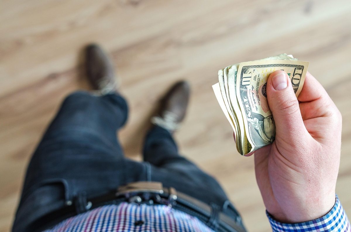 man looking down at money in his hand
