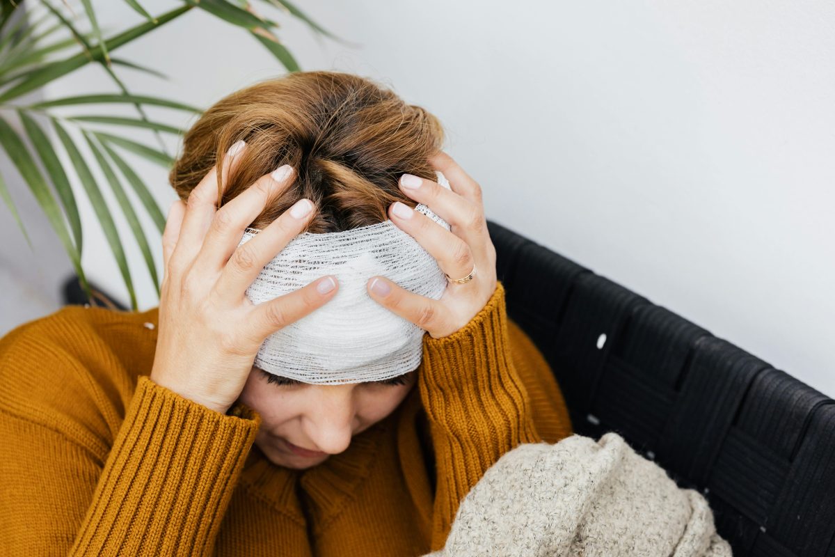 woman holding her head wrapped with a bandage