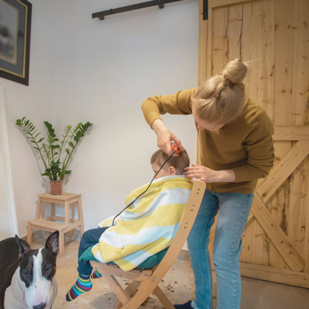 woman cutting a boys hair while boy sits in a chair