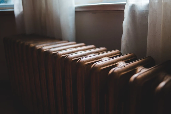 Old radiator near windowsill at home in daylight