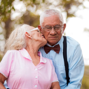 elderly woman kisses elderly man on the cheek