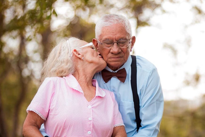 elderly woman kisses elderly man on the cheek
