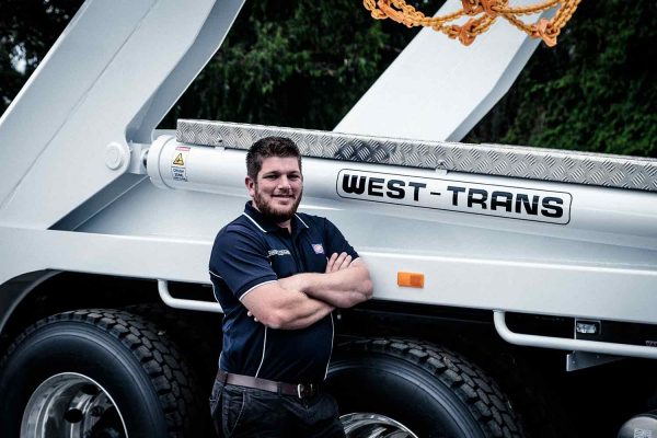 man standing beside white west-trans truck