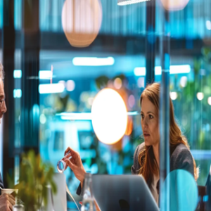Business meeting where three people are discussing, "What is AI enablement?" in a modern glass-walled office.