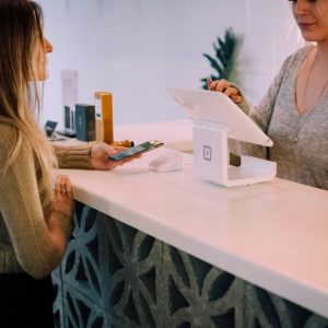 woman standing at a checkout counter holding her phone