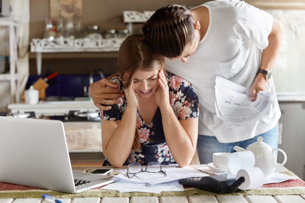 man hugging woman in kitchen looking at papers