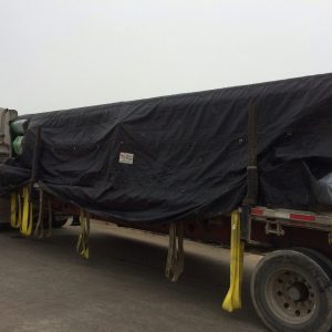 man in yello vest putting tarp on truck trailer