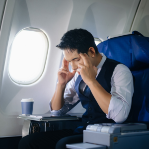 man sitting in airplane rubbing his temples