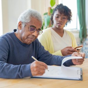 elderly man looking at papers with pen in his hand
