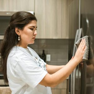 a close up of woman wiping a refrigerator