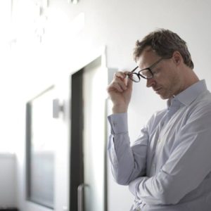 Stressed man holding his glasses.