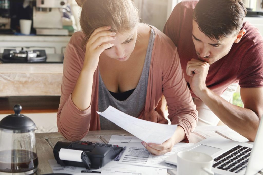 stressed young couple looking at paperwork