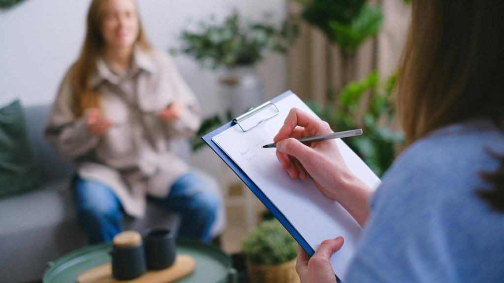 person writing on a notepad and talking to a client