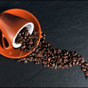 A cup and saucer with coffee beans spilling out of it